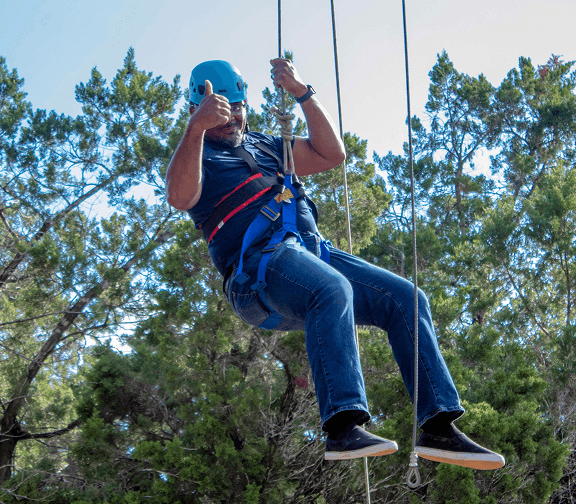 Employee riding a zip line during an outdoor team-building activity.