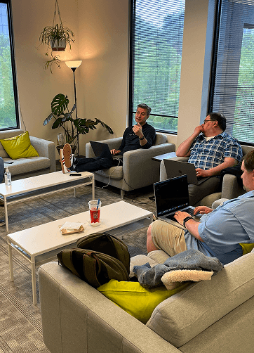 Employees collaborating in a casual office meeting area.